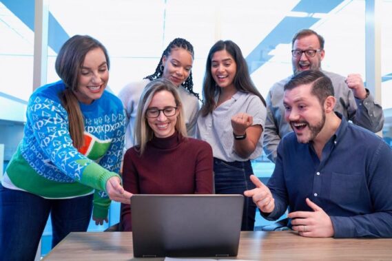 People surrounding a laptop celebrating success with affiliate marketing
