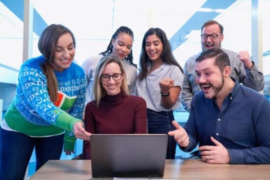 People surrounding a laptop celebrating success with affiliate marketing