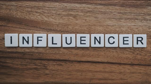 Words influencer in block letter on brown desk Words influencer in block letter on brown desk