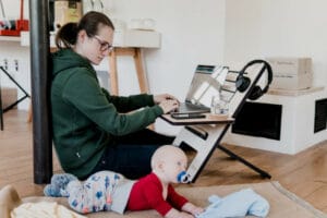 Work From Home Benefits with Mother working with here laptop while looking after her child